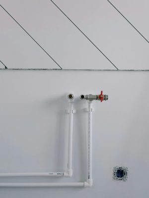 White wall with minimalist plumbing pipes and diagonal lines